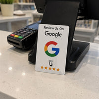 La tarjeta NFC blanca apoyada junto al datáfono en el mostrador de un comercio