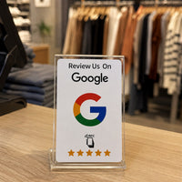La tarjeta NFC blanca en un expositor de metacrilato sobre el mostrador de una tienda de ropa