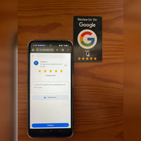 La tarjeta NFC negra junto a un móvil con la página de reseñas de Google ya abierta y las cinco estrellas marcadas